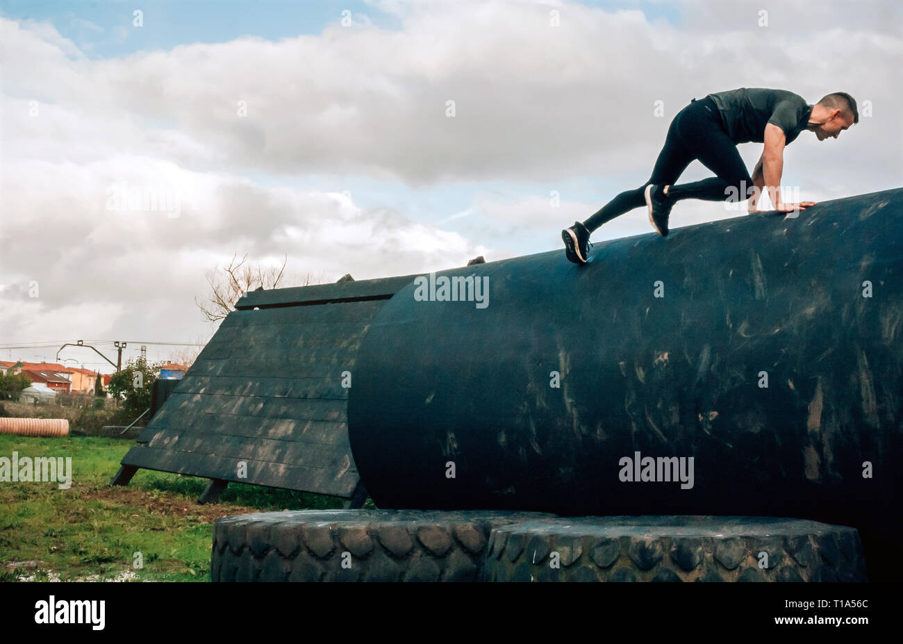 Hombre en una carrera de obstáculos subiendo un tambor Foto de stock
