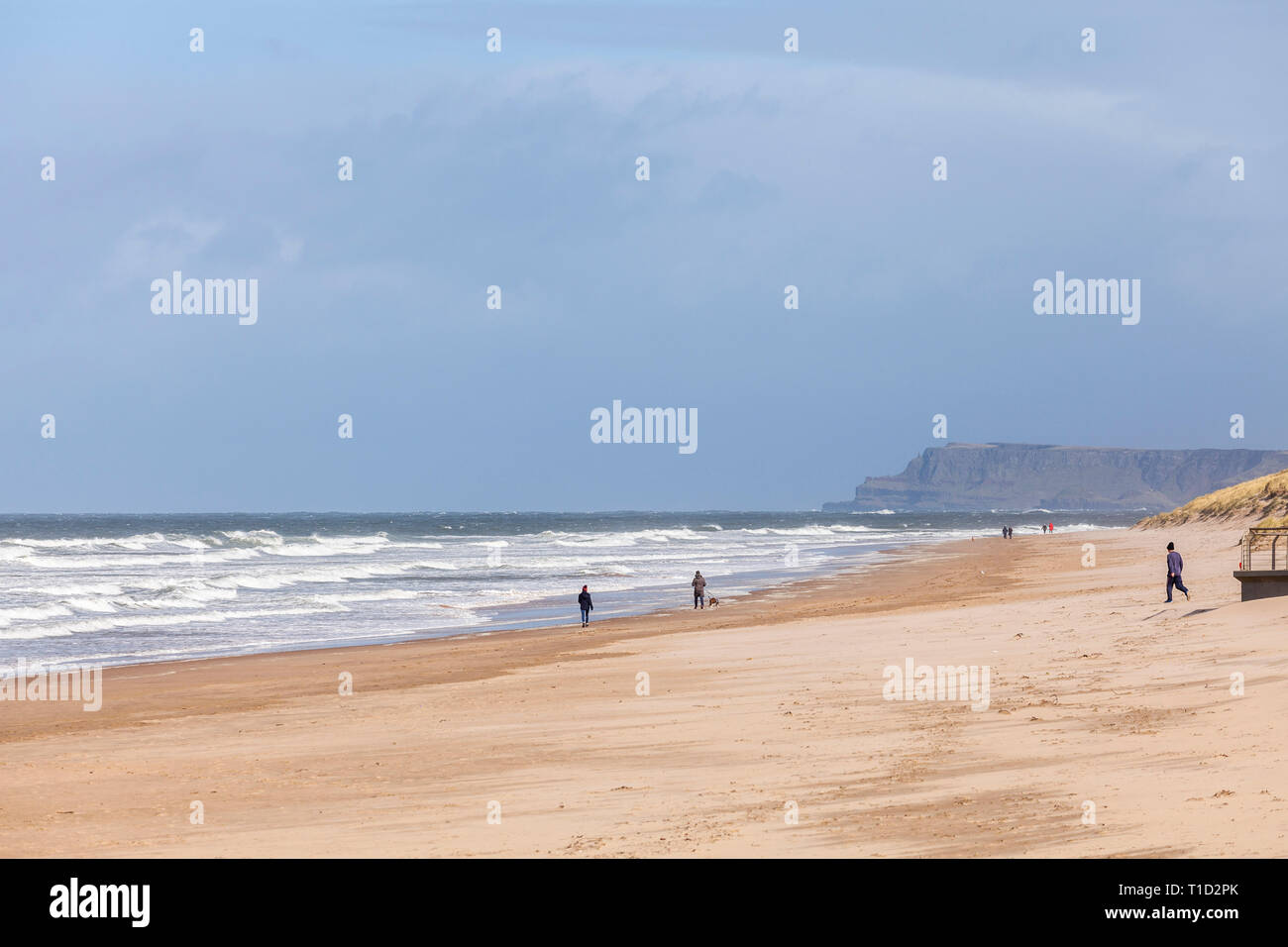 La gente caminando en medio Strand playa, Portrush en un tempestuoso día de marzo Foto de stock