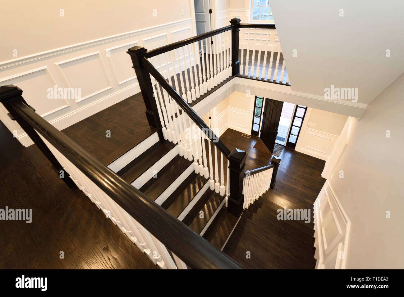 Escalera. Escalera interior de diseño moderno con suelos de madera oscura y revestimientos de paneles blancos Foto de stock