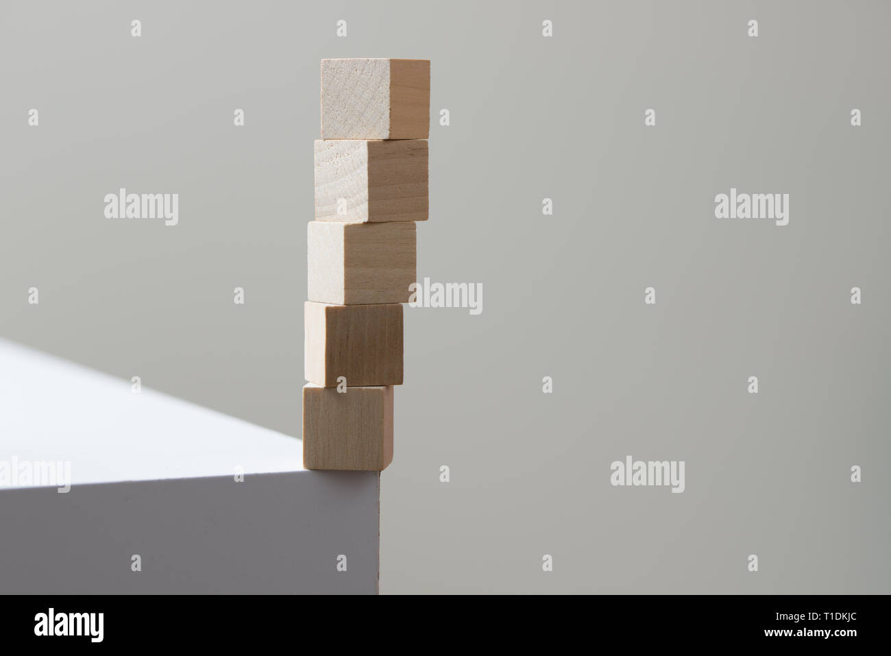 Cubos de madera en equilibrio en el borde de la mesa para el concepto de riesgo Foto de stock