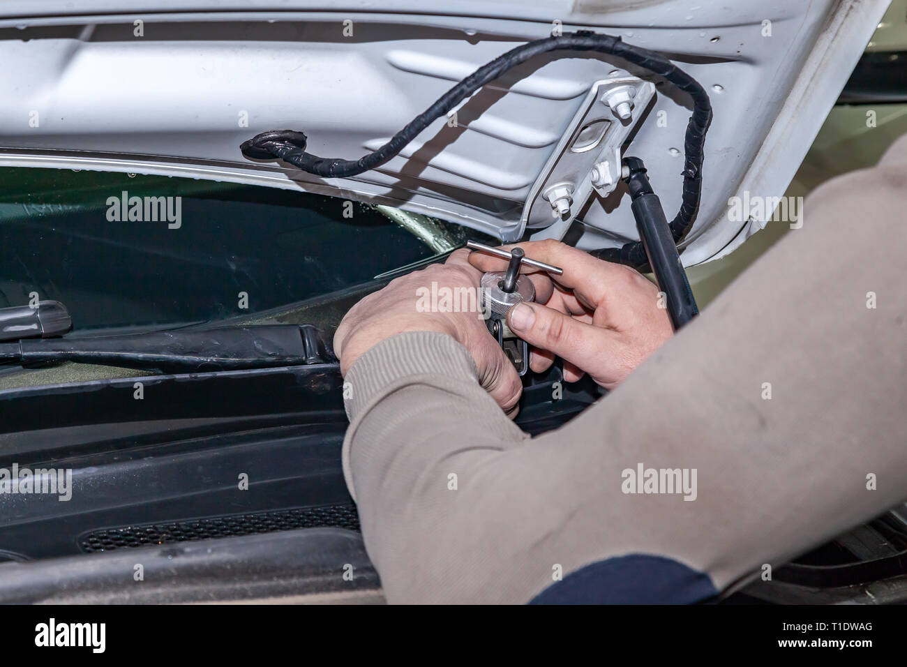 Un coche reparador desatornilla partes limpiaparabrisas con una llave con  un asa verde en el compartimiento del motor en un taller de reparación de  vehículos Fotografía de stock - Alamy