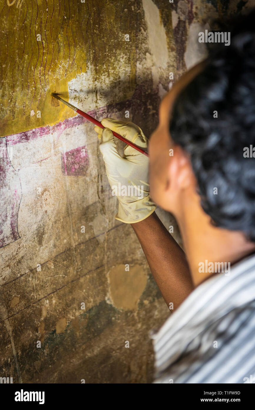 Un artesano trabaja concienzudamente para restaurar parte de la mundialmente famosa murales en los Templos Cueva de Dambulla, Sri Lanka. Foto de stock