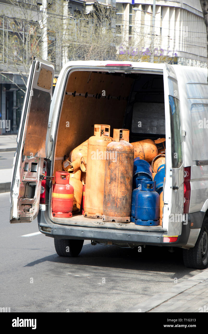 Cilindro de tamaño y color diferente de botellas de gas almacenado en una camioneta de entrega troncal para rellenar y alimentación Foto de stock