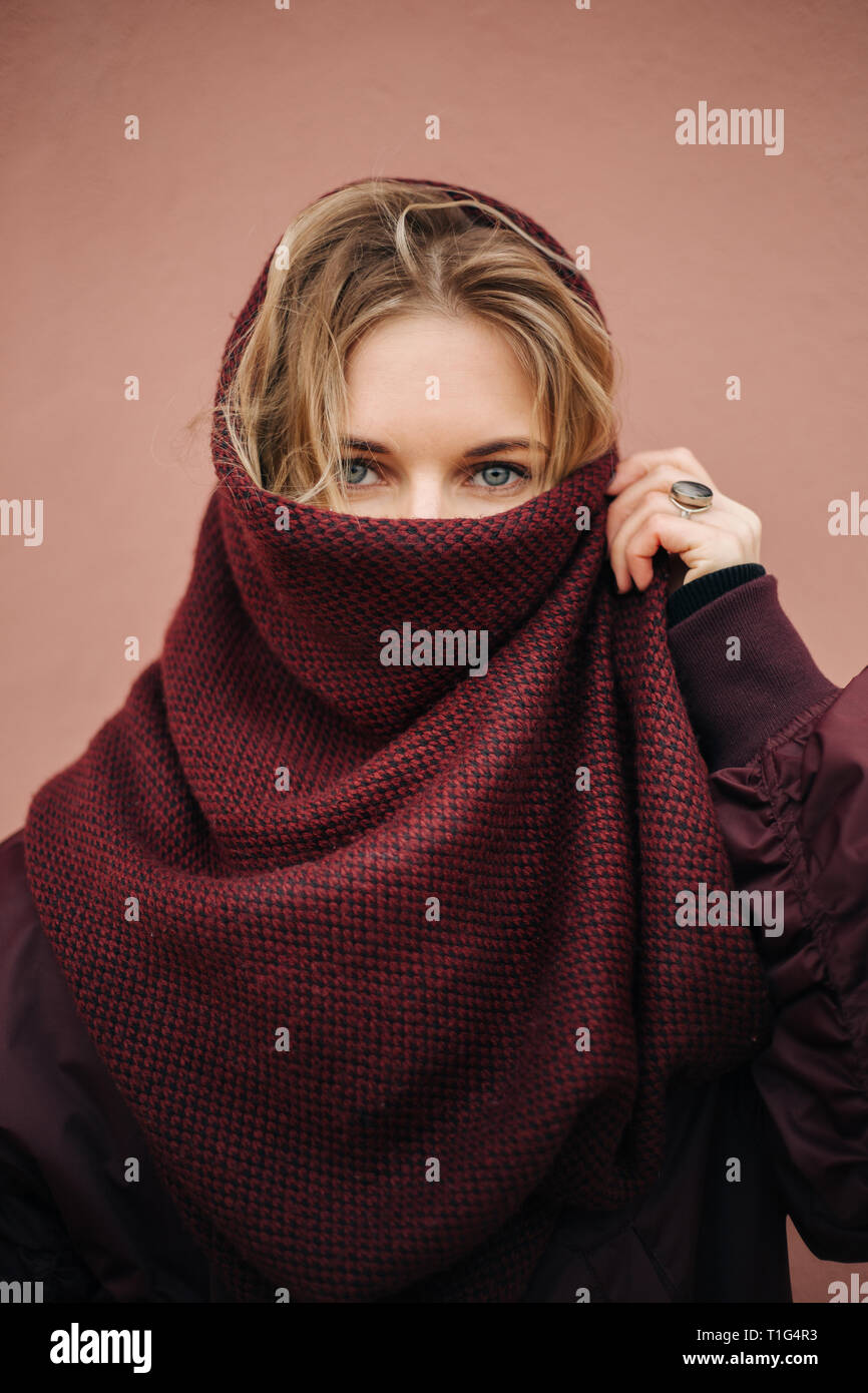 Foto de joven mujer rubia con bufanda cerrada cara en el fondo de la pared  Fotografía de stock - Alamy