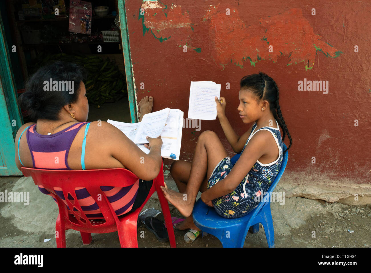 Niña y madre comprobando los deberes en Carti isla, uno de los Guna / aldeas indígenas Kuna Yala. Las islas de San Blas, Panamá. Oct 2018 Foto de stock
