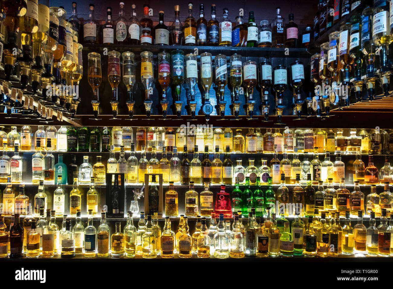 Una amplia selección de whiskys escoceses iluminado en estantes de vidrio y en óptica, Escocia Foto de stock
