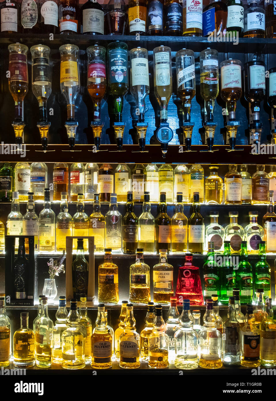 Una amplia selección de whiskys escoceses iluminado en estantes de vidrio y en óptica, Escocia Foto de stock