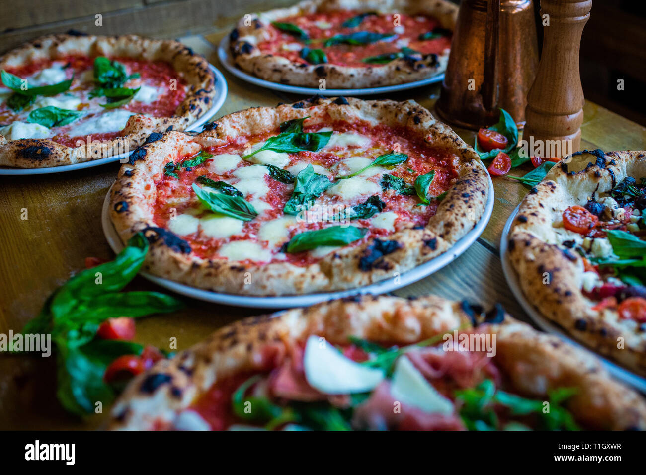 Pizzas de leña tradicional napolitano sobre la mesa de madera en una pizzeria trattoria italiana Foto de stock