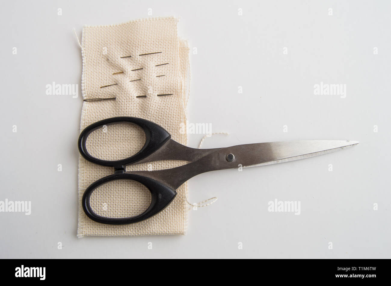 Materiales de costura tijeras, aguja, telas en blanco, el concepto de la tabla superior, minimalista y accesorios para adaptar artesanal. Foto de stock
