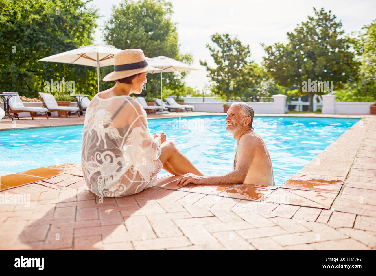 Feliz pareja relajante en la soleada piscina resort Foto de stock