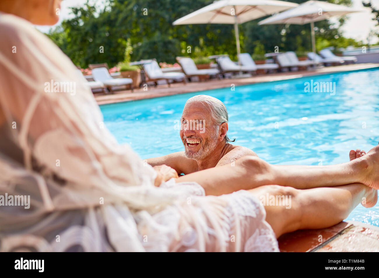 Feliz pareja relajante en la soleada piscina resort Foto de stock