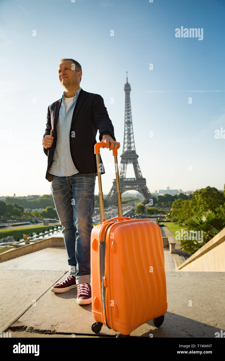 Guapo con maleta naranja de pie en la plaza Trocadero. El paisaje urbano de  París, vista de la Torre Eiffel. Concepto de viaje Fotografía de stock -  Alamy
