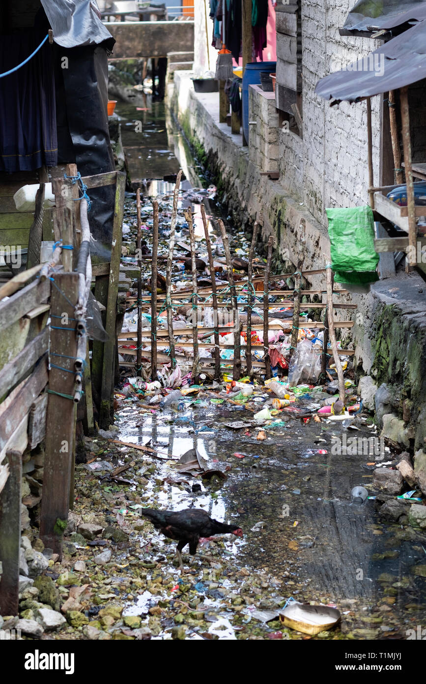 Basura y desechos de plástico desechados en una vía navegable en Sawai, un pequeño pueblo de pescadores en la isla de Seram, Indonesia Foto de stock
