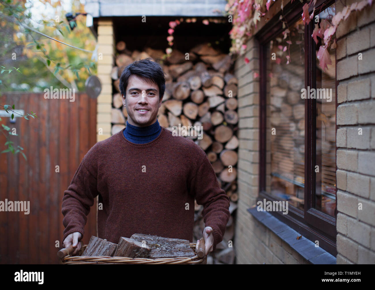 Retrato hombre llevando leña en otoño patio Foto de stock