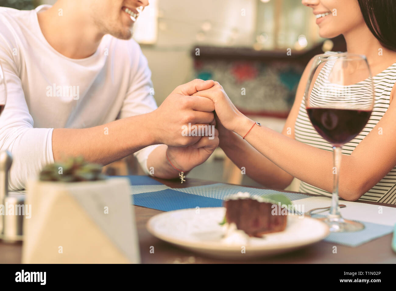 Adorable hombre sentimental sostiene suavemente las manos de su novia Foto de stock