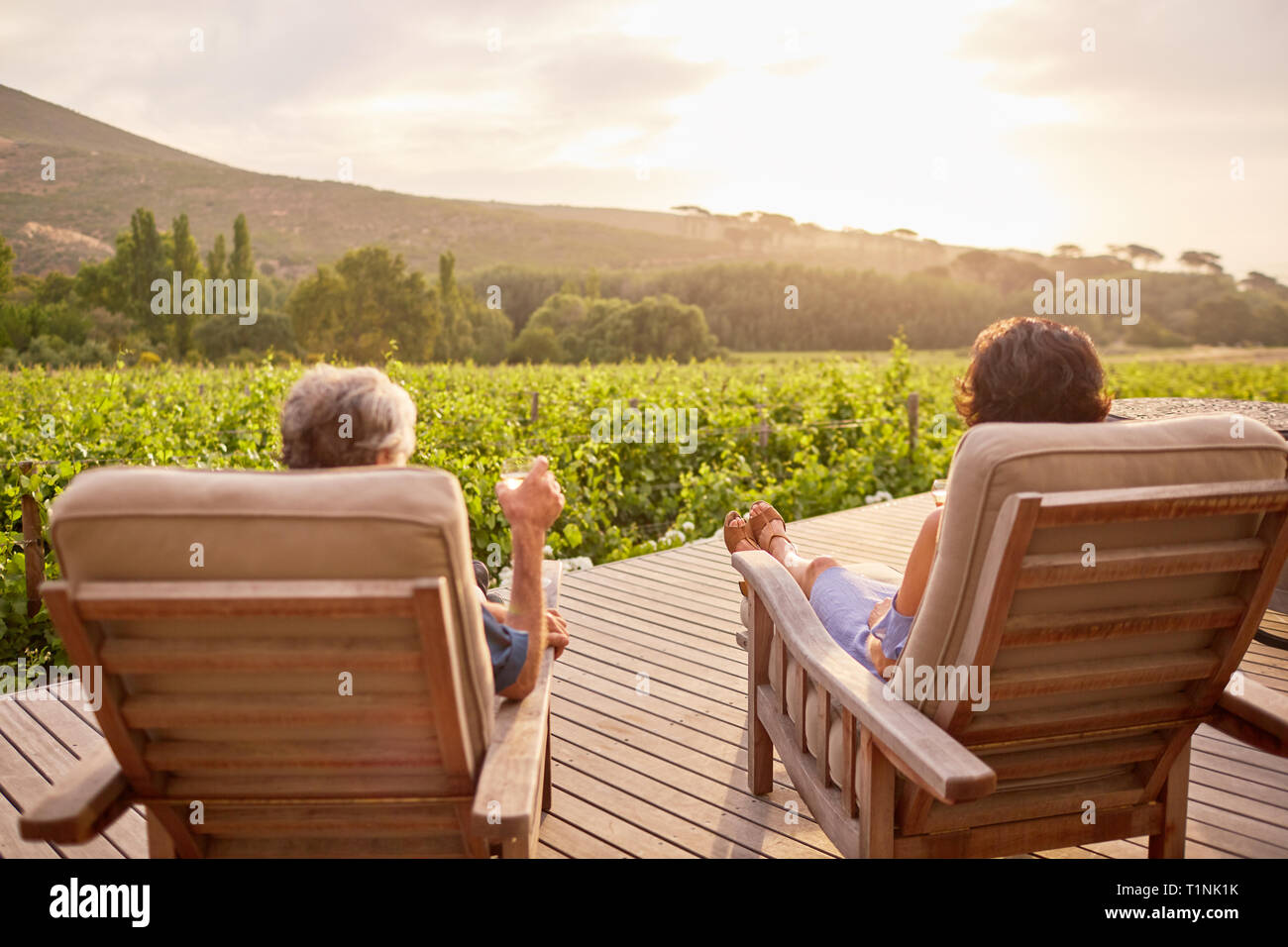 Par relajarse, beber vino en sunny, complejo idílico patio Foto de stock