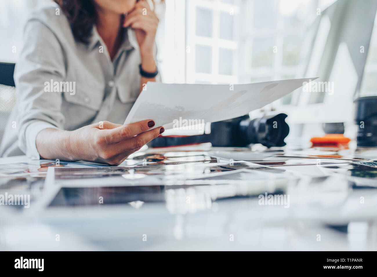 Mujer trabajando en su estudio. Captura recortada de una mujer fotógrafa controlar impresiones tras el desarrollo. Foto de stock