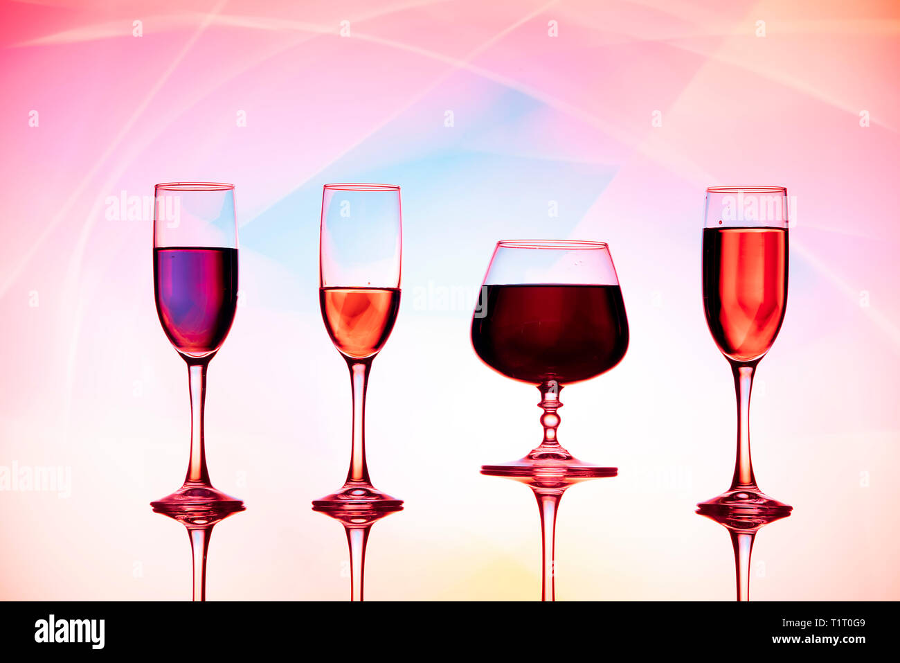 Cuatro copas de vino de agua están sobre la mesa, detrás de un colorido  fondo.Gafas reflejadas en el cristal Fotografía de stock - Alamy