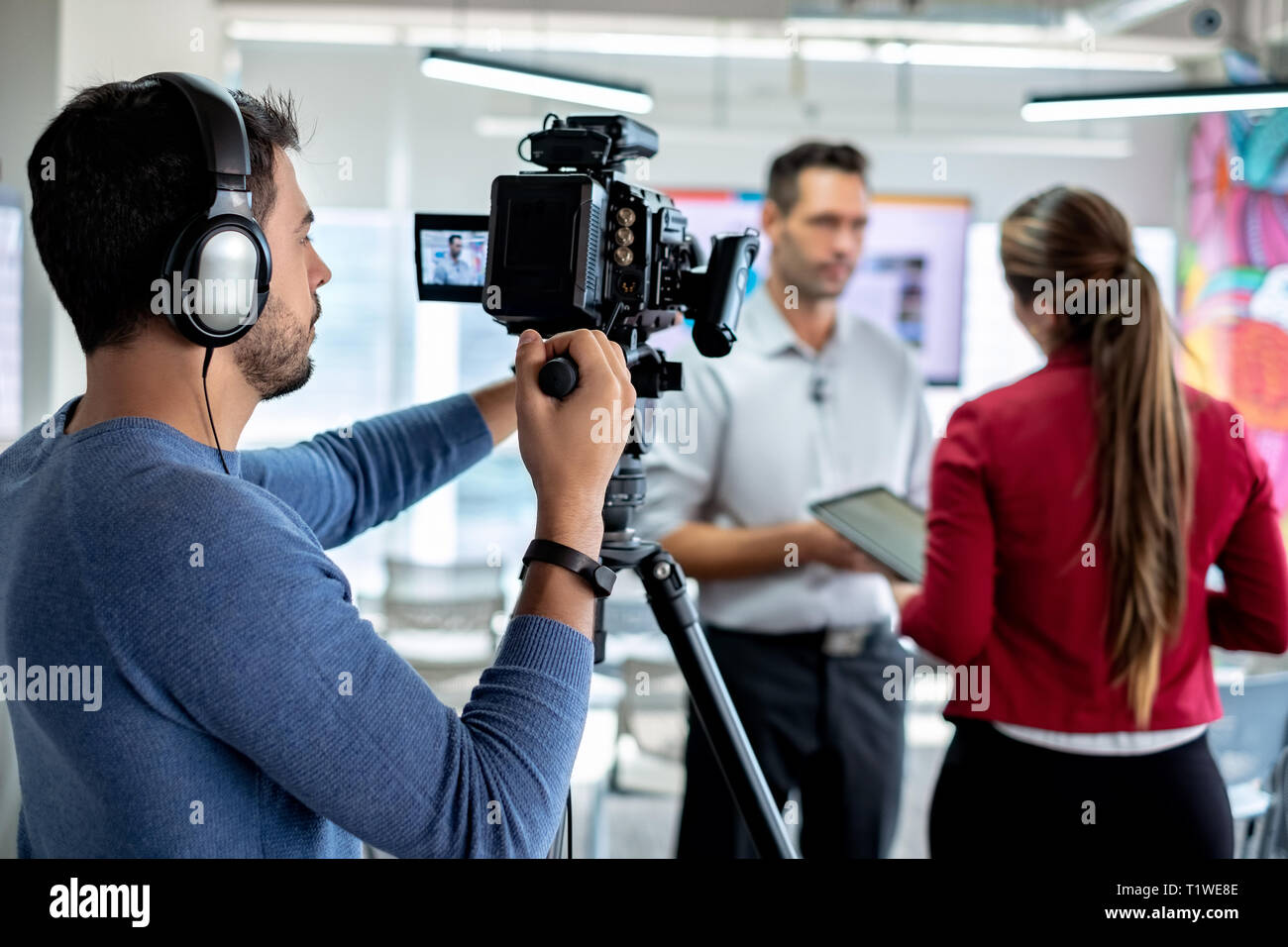 Feliz empresario corporativo durante la entrevista con el periodista. Manager contestar la pregunta en la oficina. Mujer joven a trabajar como periodista financiera Foto de stock