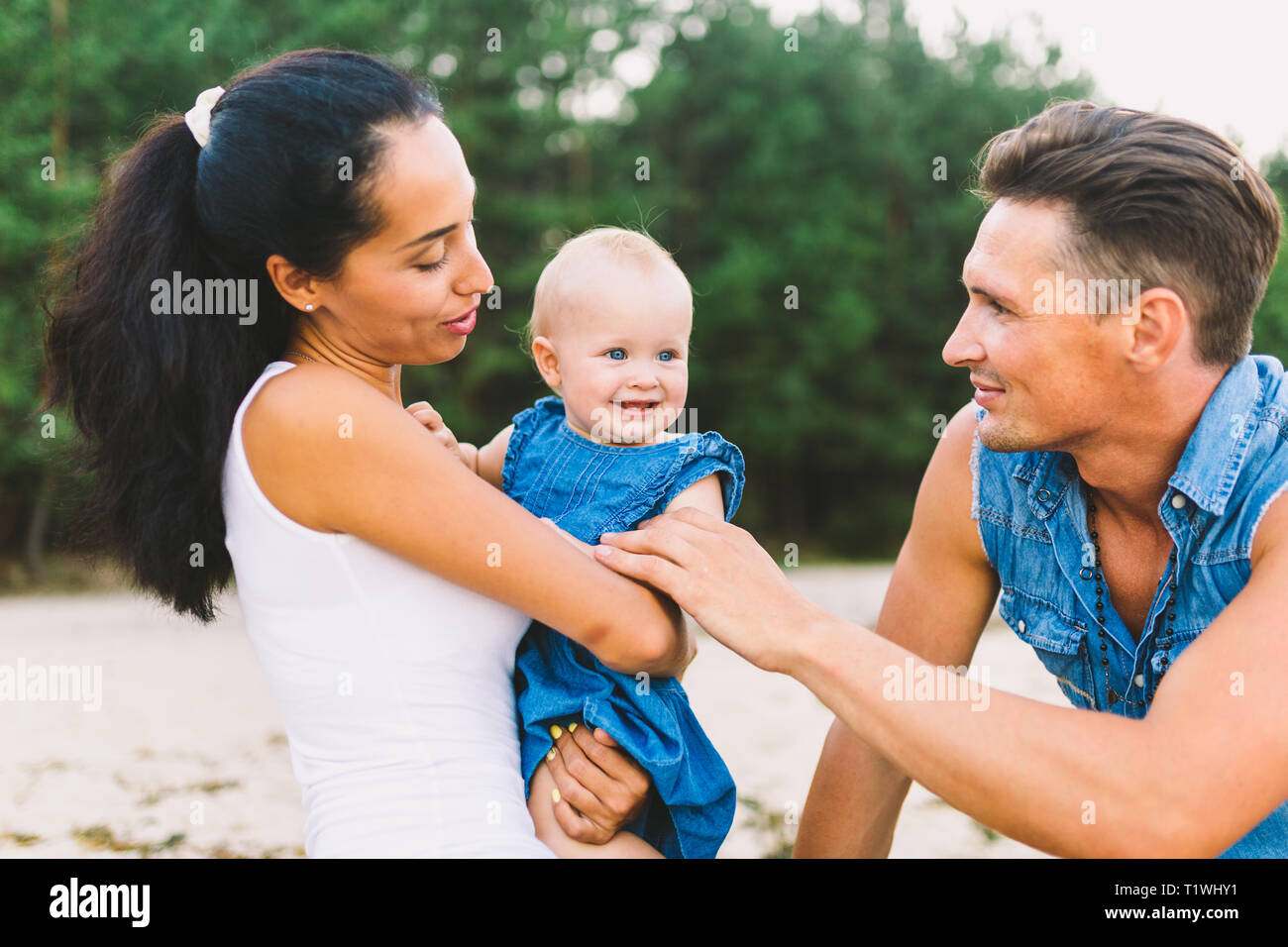 Una Joven Y Hermosa Familia De Tres Mama Papa E Hija En Los Brazos De Mi Padre Jugar Alegres Sonrisas En La Playa De Arena En La Playa En Verano Fotografia De
