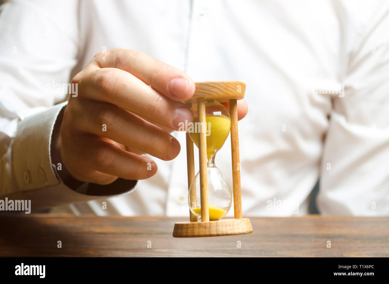 Reloj de arena en las manos de una persona en una camisa blanca. La gestión de la empresa. Gestión del tiempo aumenta la eficiencia, reduce los costos y la burocracia. Logística Foto de stock