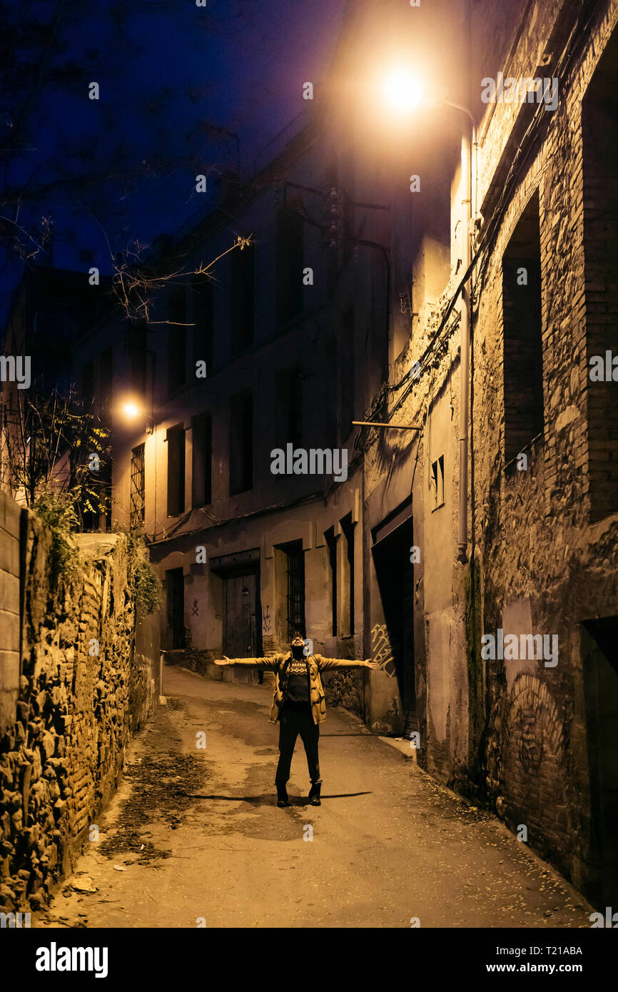 España, Igualada, hombre de pie debajo de una lámpara de la calle en la  ciudad con los brazos abiertos por la noche Fotografía de stock - Alamy