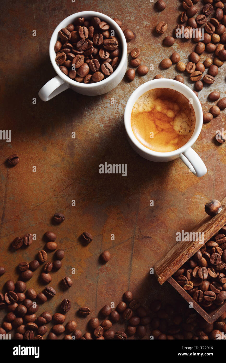 Taza de café con granos de café esparcidos en una superficie rústica. Foto de stock