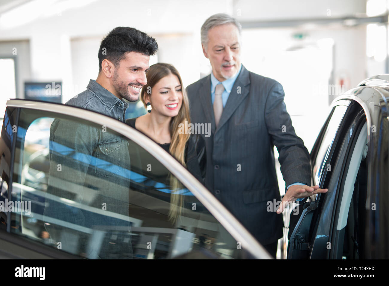 Feliz Familia Joven Hablando Con El Vendedor Y Eligiendo Su Nuevo Coche En Un Showroom 