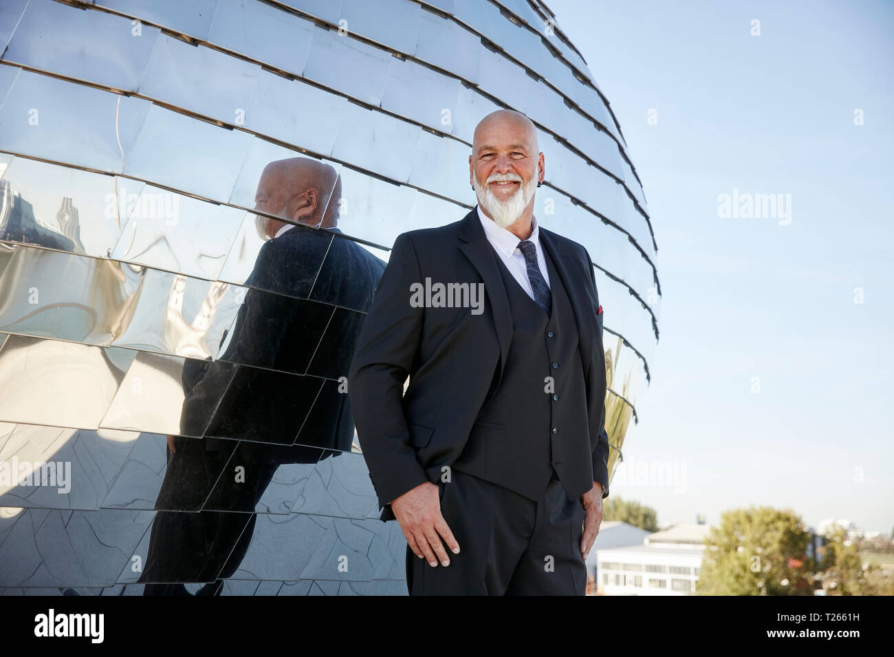 Empresario elegante en la ciudad sonriente, riendo delante del espejo fassade Foto de stock