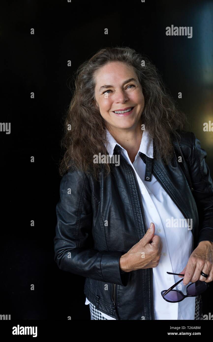 Retrato de mujer madura sonriente vistiendo la chaqueta de cuero negro Foto de stock