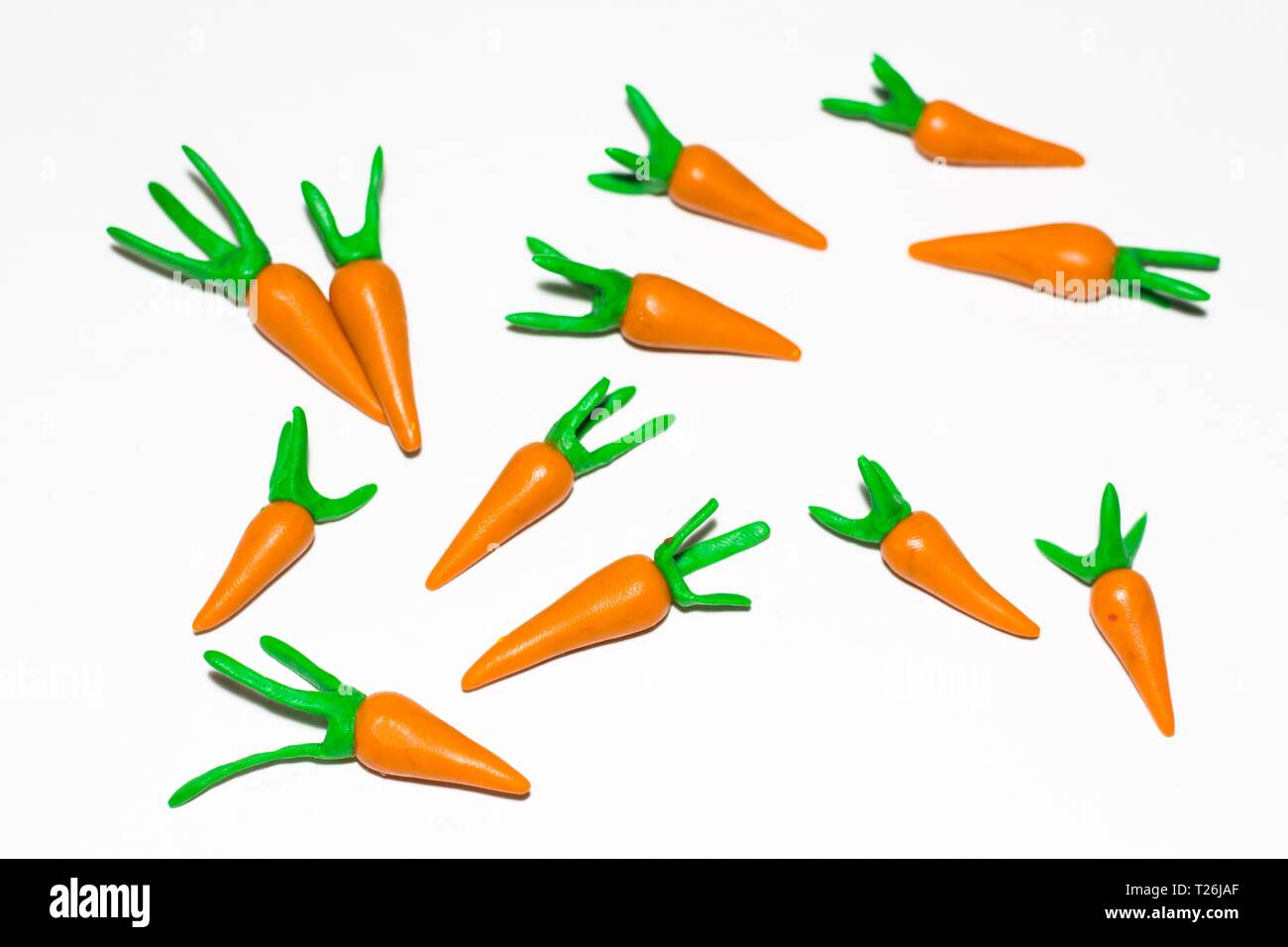 Varias zanahorias sobre un fondo blanco hecho de plastilina. Las zanahorias mentira aleatoriamente con cada otro. Foto de stock