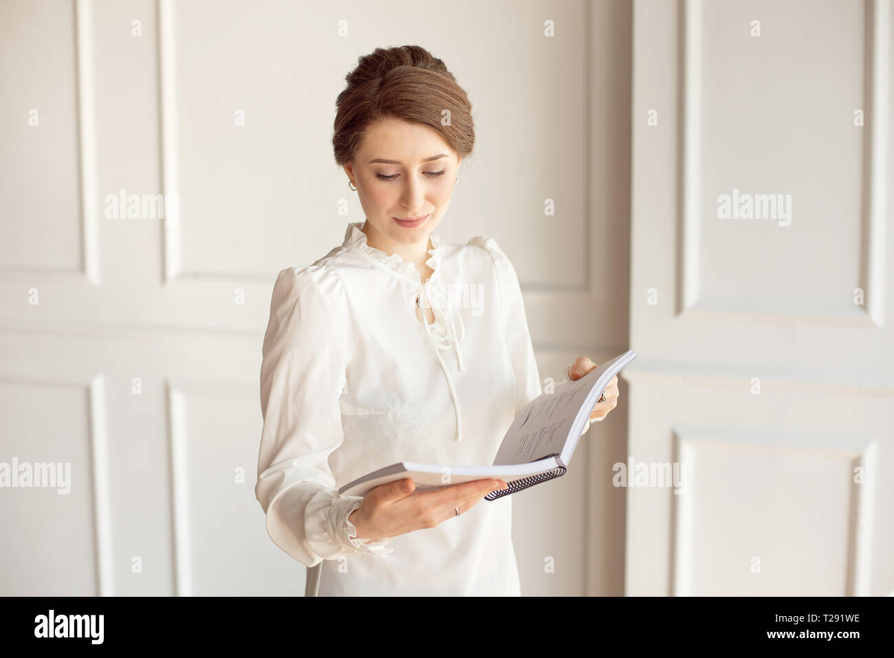 Mujer de negocios en una camisa blanca y pantalón negro busca documentos en  manos Fotografía de stock - Alamy