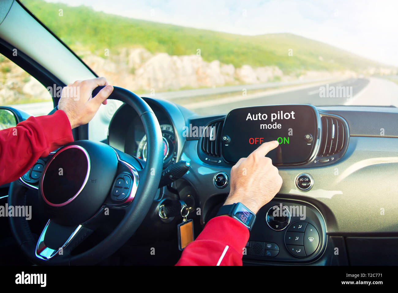 Las manos masculinas con smart watch al encender el piloto automático en el modo de pantalla de coche en la autopista Foto de stock