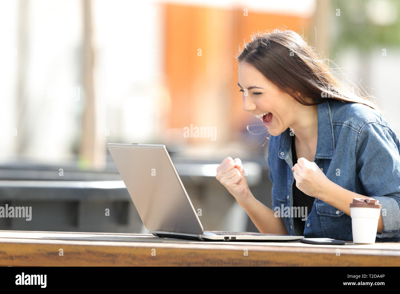 Emocionados mujer comprobación de contenido en línea portátil sentado en un parque Foto de stock