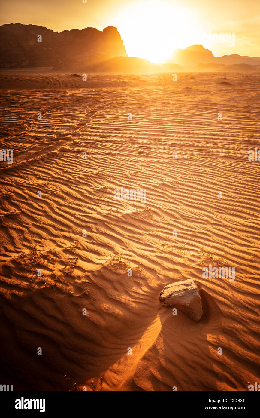 Paisaje tomadas en el momento de la puesta de sol, Wadi Rum, Jordania, detalle del desierto de dunas de arena y roca en el primer plano. Foto de stock