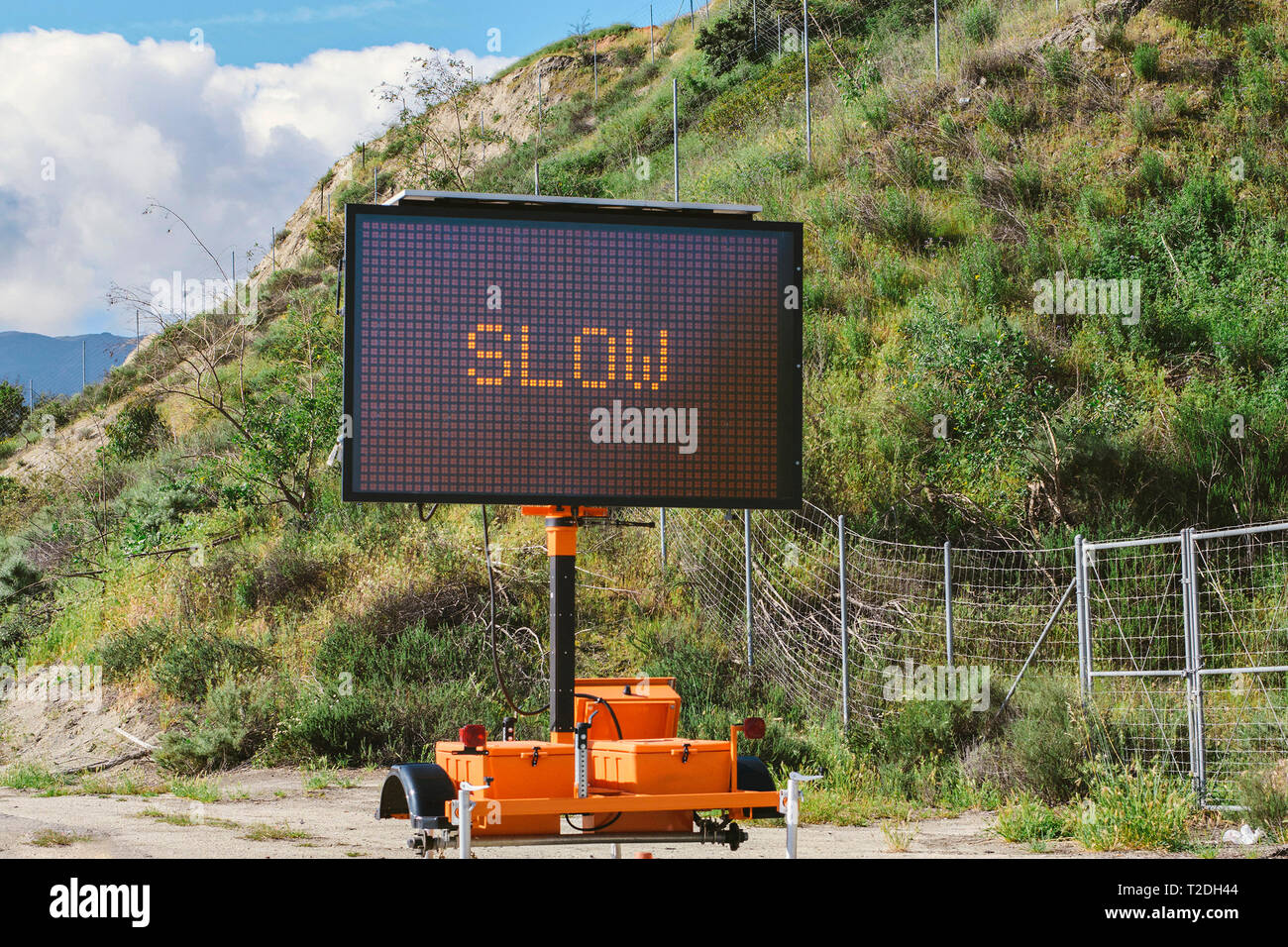 Signo lenta electrónica en una carretera con el cielo y las nubes en la  distancia Fotografía de stock - Alamy