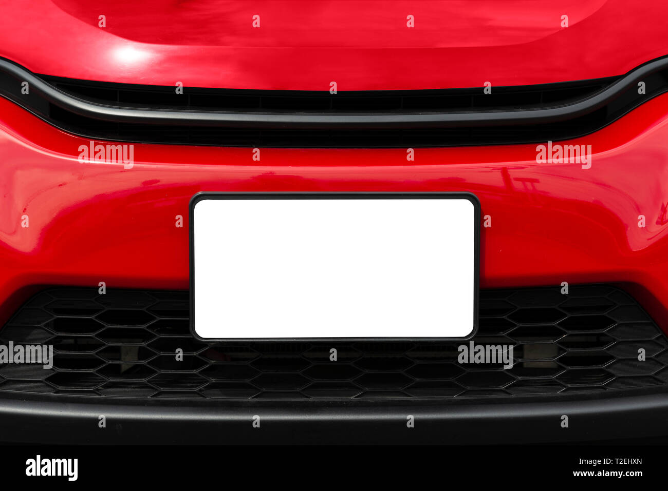 Disparo horizontal de una placa de matrícula delantera en blanco en un coche rojo con espacio de copia. Foto de stock