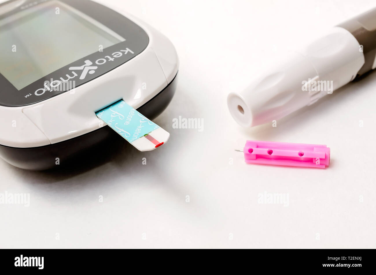 Un Keto-Mojo cetona y medidor de glucosa en sangre es la foto en blanco,  junto con las tiras de prueba de glucosa y cetonas, las agujas desechables  y lancet dispositivo Fotografía de