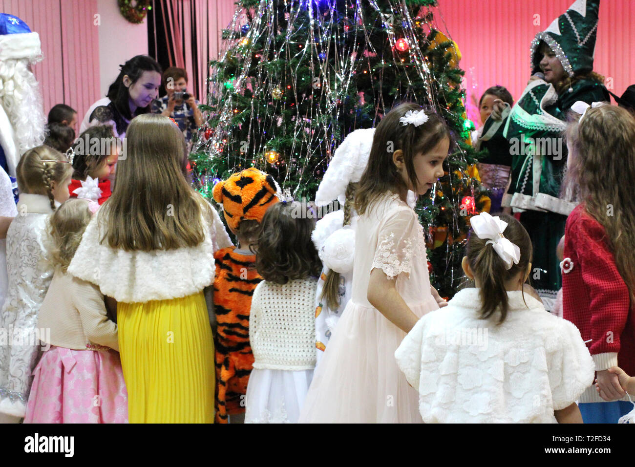 Una gran cantidad de hermosos niños vestidos elegantes en las niñas y los niños en Fancy Dress divirtiéndose en la fiesta año nuevo alrededor del árbol de Navidad Fotografía de stock -