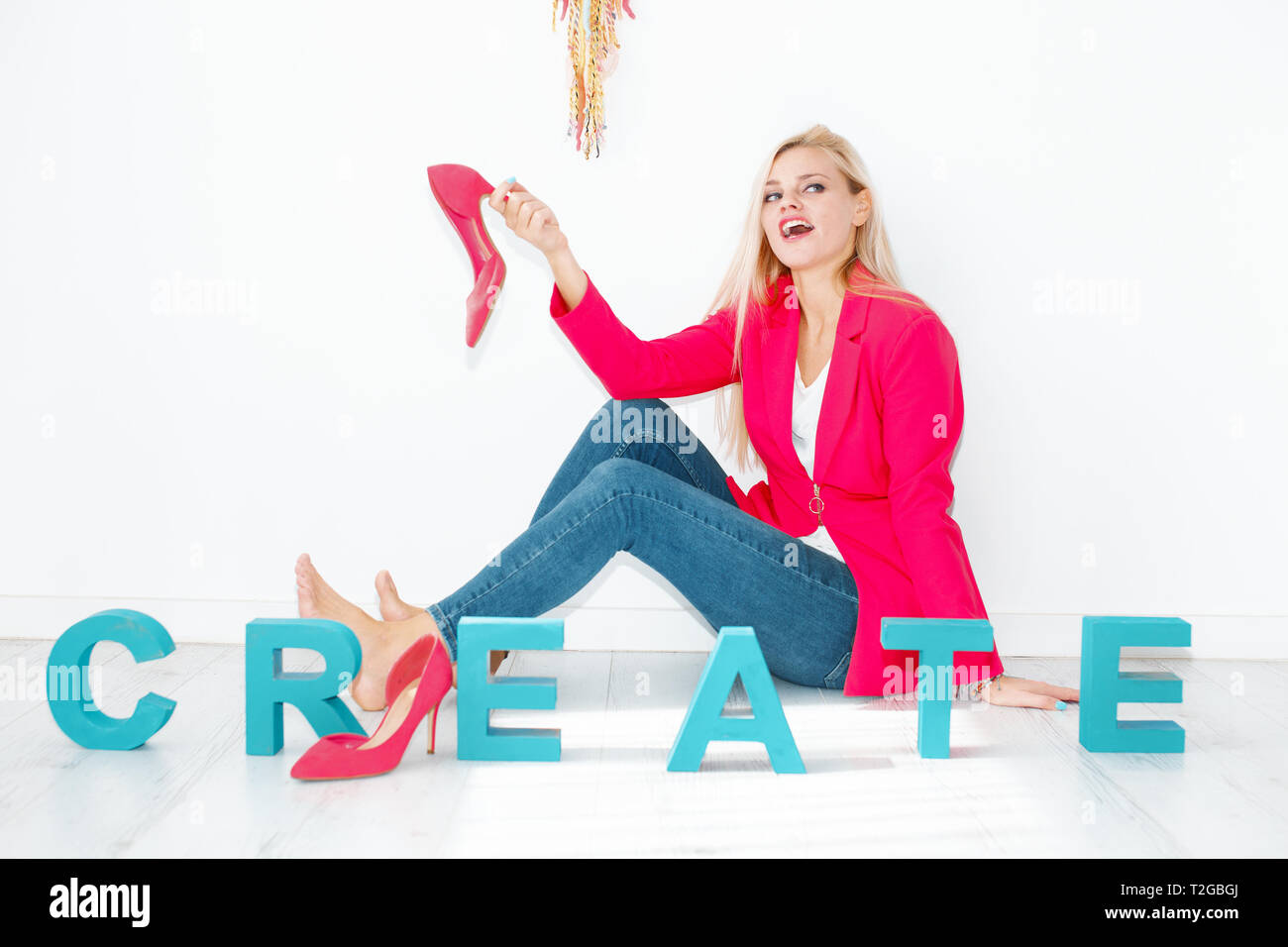 Feliz joven creativo mujer rubia sosteniendo los tacones altos en casa Foto de stock