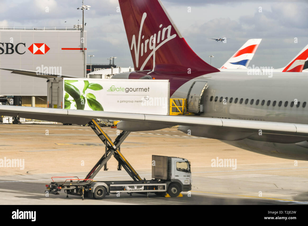 Del aeropuerto de Heathrow de Londres, Inglaterra - Febrero de 2019: un vehículo elevador de tijera de Gate Gourmet catering de carga a través de la puerta trasera de un Virgin Atlantic jet Foto de stock