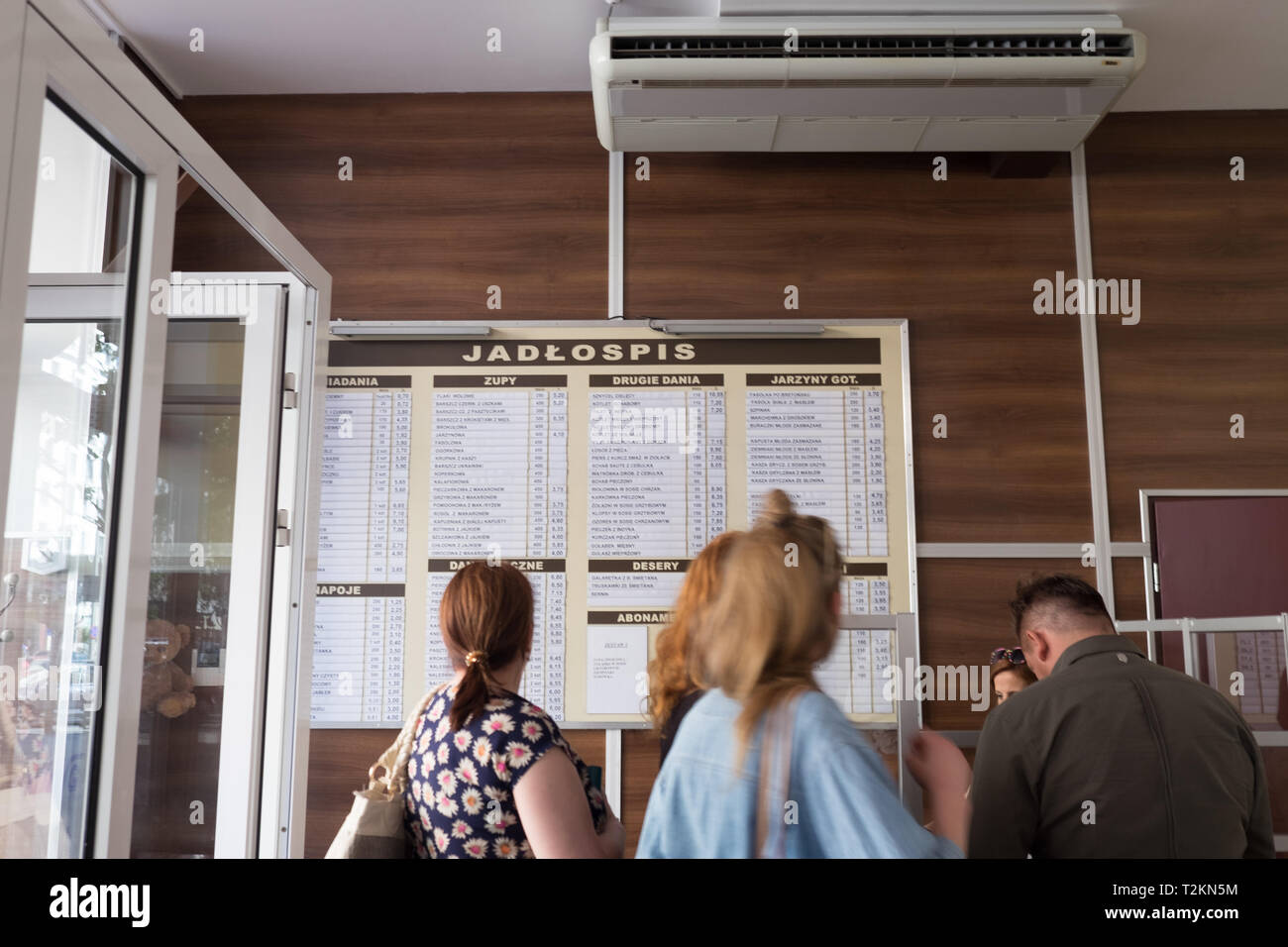 Gente esperando en línea mirando el menú en el Bar Bambino, milk bar en Varsovia, Polonia. Foto de stock