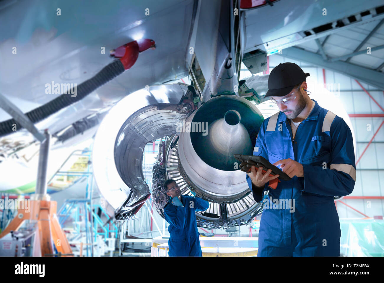 Imagen compuesta de trabajadores de mantenimiento en fábrica con la tableta digital Foto de stock