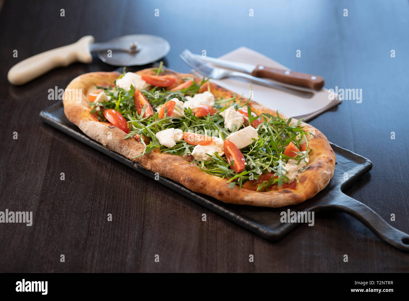 Queso, tomate y rúcula Pinsa pizza romana, una mezcla de grasas saturadas y azúcares reductores Foto de stock