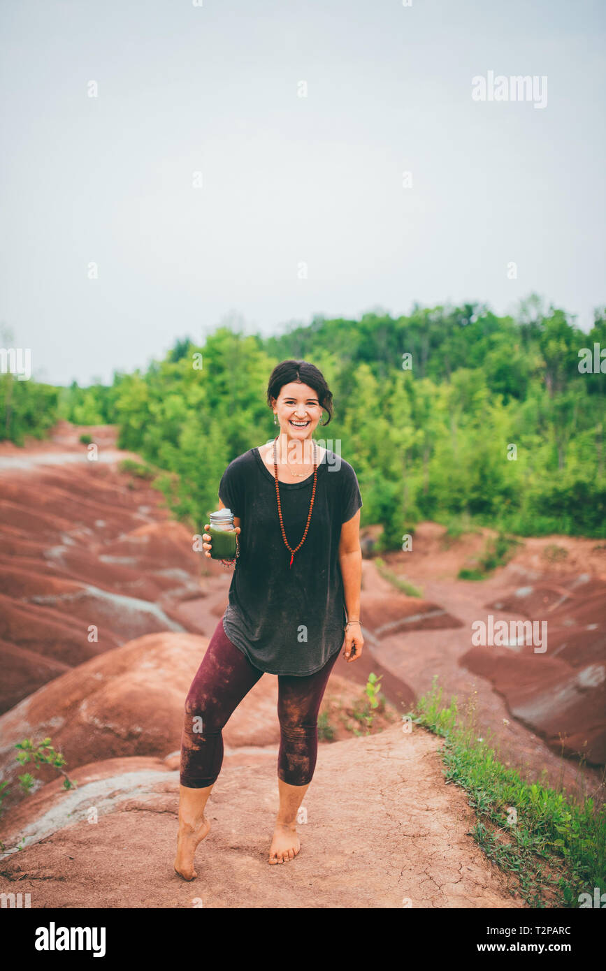 Mujer beber jugo verde en roca Foto de stock