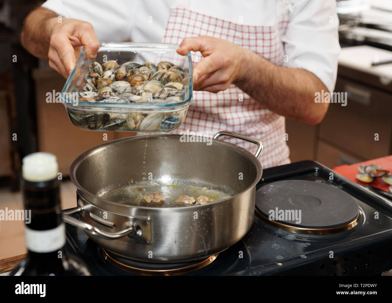 Chef es agregar agua de almejas vivas donde alojarse para hacer caldo perfecto Foto de stock