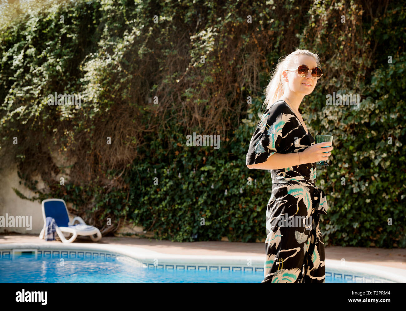 Mujer con bebida relajante con piscina Foto de stock