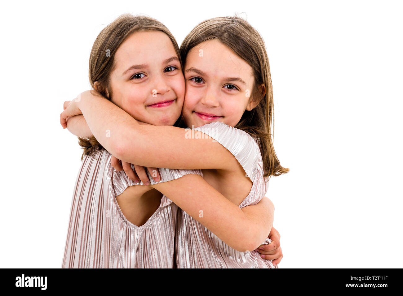 Dos gemelas hermanas están posando para la cámara. Feliz hermanas gemelas  en vestidos mirando la cámara, riendo, sonriendo, abrazando las manos  Fotografía de stock - Alamy