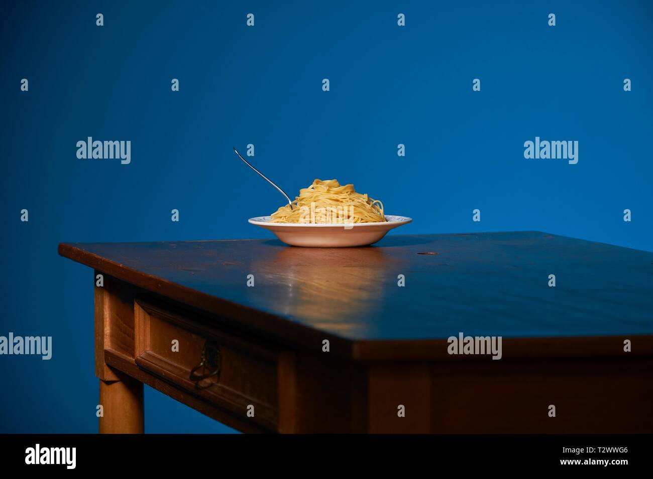Eine Porción de spaghetti steht auf einenem Holztisch vor einer varita farbenen gasolina Foto de stock