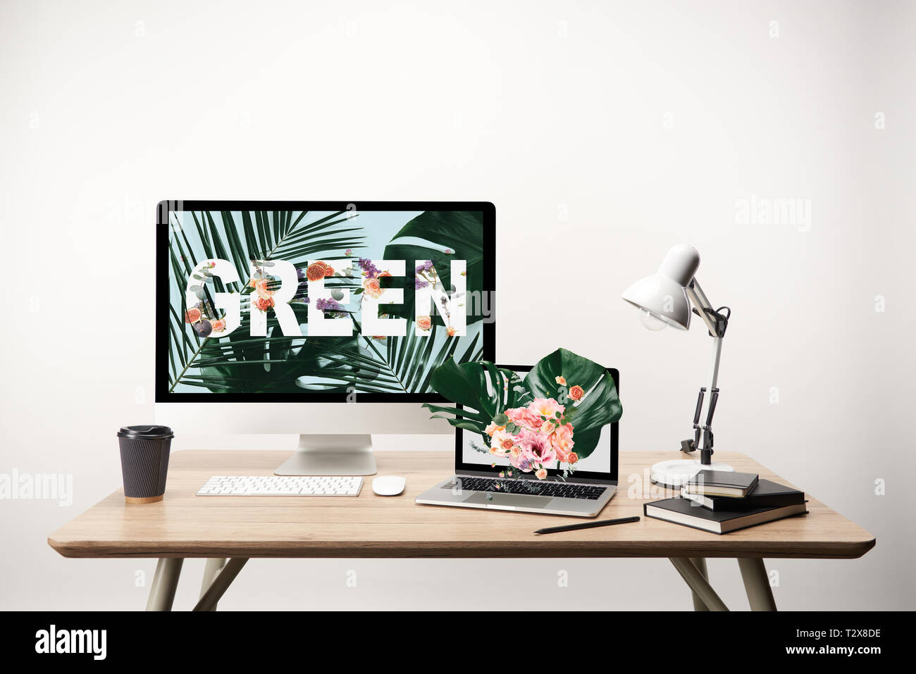 Ordenador con letras verdes y hojas de monstera ilustración en el monitor sobre la mesa de madera Foto de stock